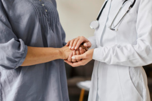 médico segura a mão de paciente em pé