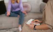 terapeuta e paciente sentadas, com a terapeuta segurando um papel nas mãos