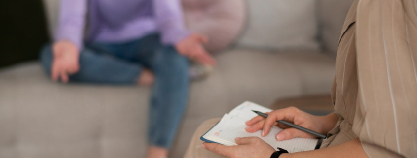 terapeuta e paciente sentadas, com a terapeuta segurando um papel nas mãos