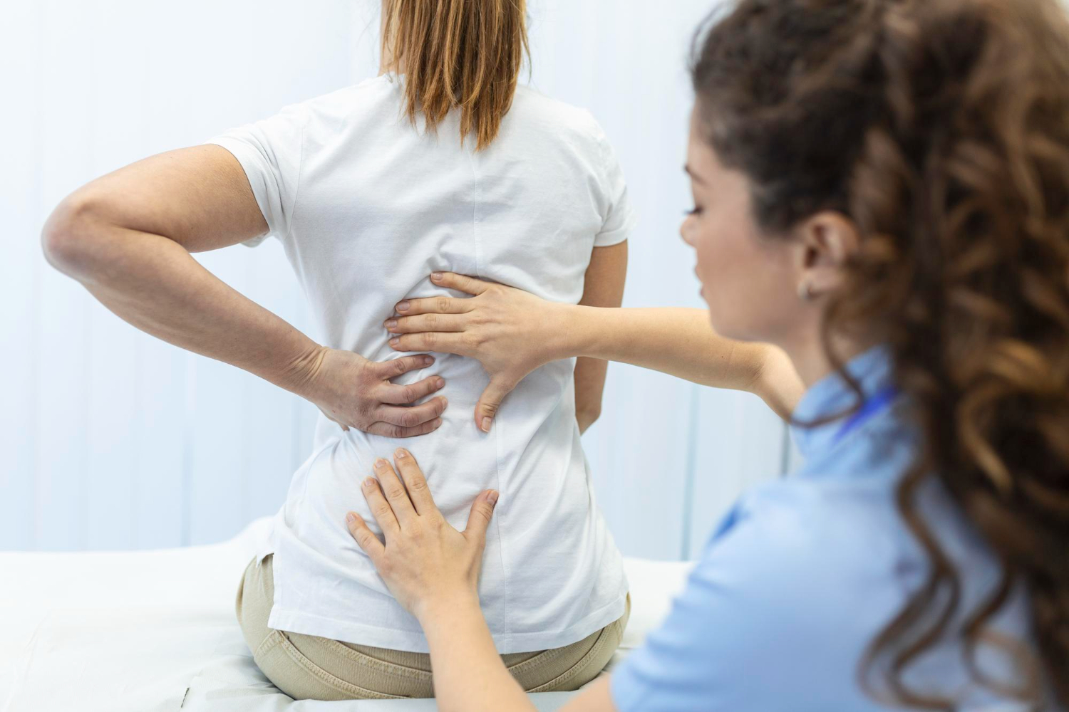 paciente sentada na maca tendo as costas examinadas