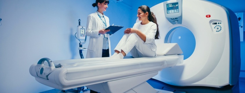 paciente sentada em máquina de ressonância com médica atendendo