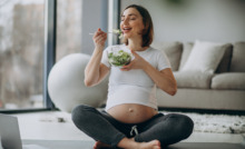 mulher grávida sentada comendo salada