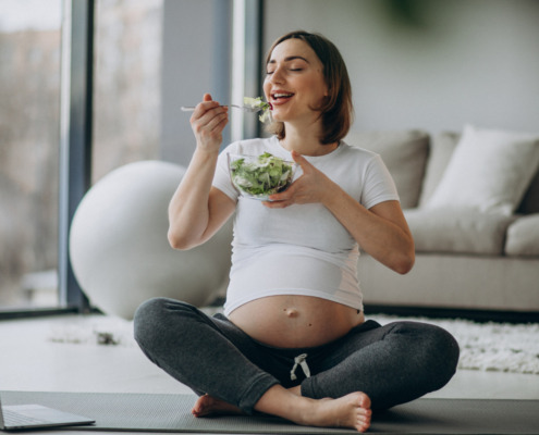mulher grávida sentada comendo salada