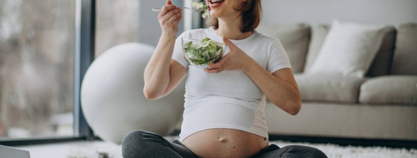 mulher grávida sentada comendo salada