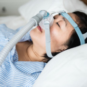 mulher deitada na cama com o aparelho CPAP