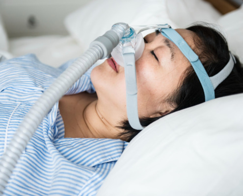 mulher deitada na cama com o aparelho CPAP