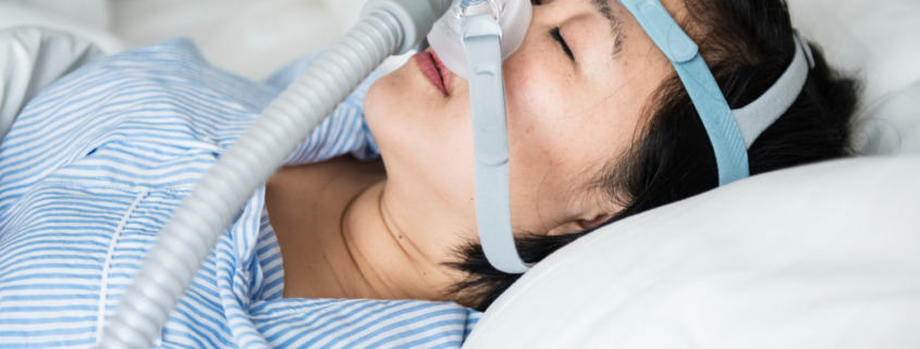 mulher deitada na cama com o aparelho CPAP