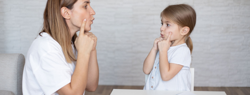 mãe e filha fazendo treinamento de fala com caderno e caneta a mesa