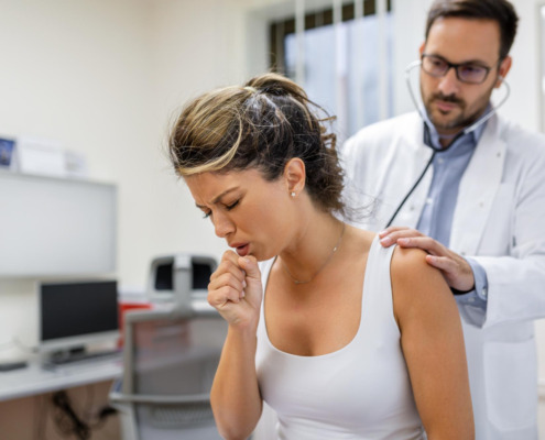 mulher tossindo em consultório médico com médico avaliando