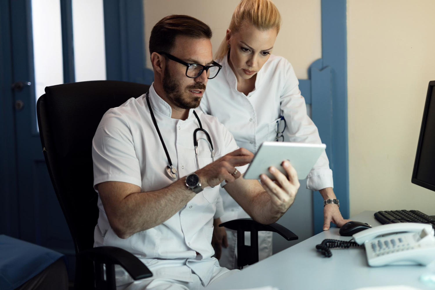 médico e médica avalia tablet em consultório