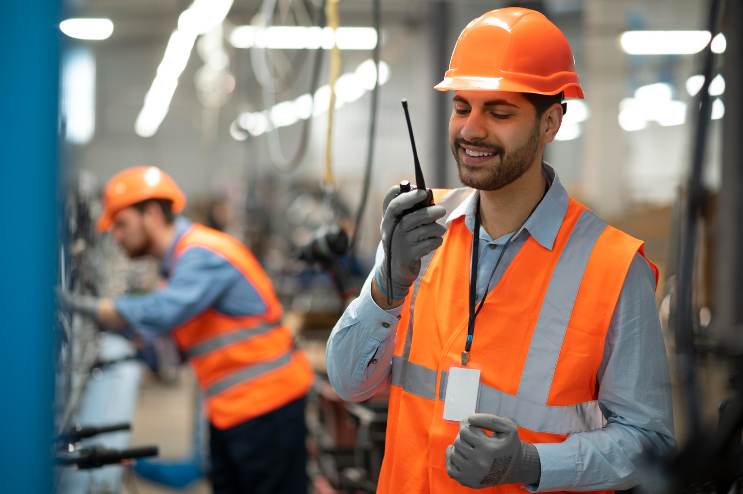 técnico de segurança do trabalho com colete laranja, capacete de segurança e falando em rádio comunicador