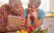 casal de idosos apoiando na mesa com legumes em sua frente