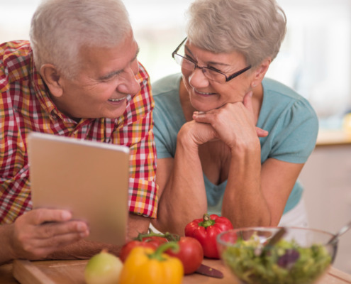 casal de idosos apoiando na mesa com legumes em sua frente