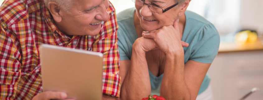 casal de idosos apoiando na mesa com legumes em sua frente