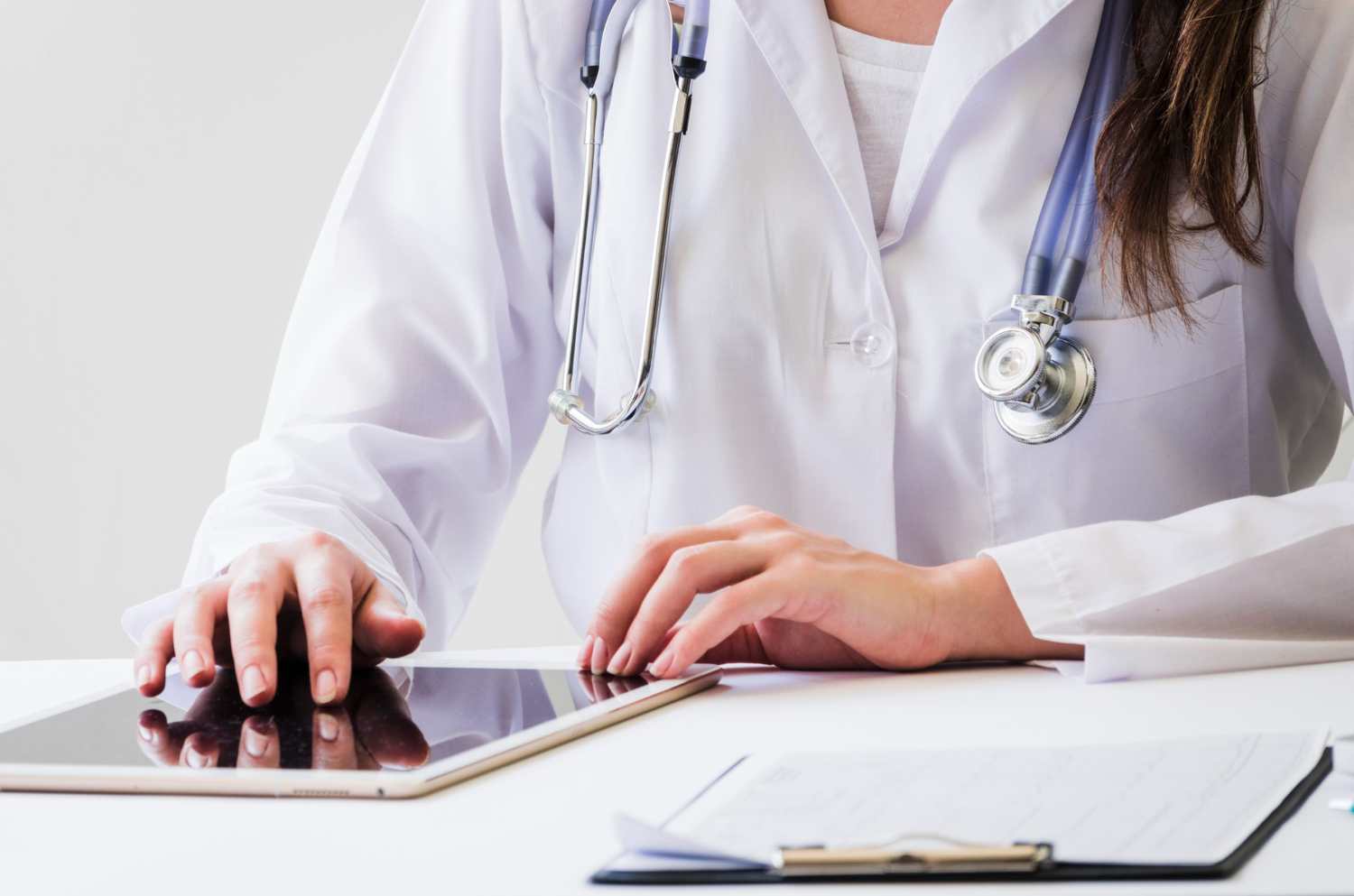 médica em consultório com a mão apoiada em um tablet