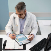 médico sentado em consultório, anotando formulário