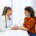 médica em consultório segura a mão de paciente e conversam