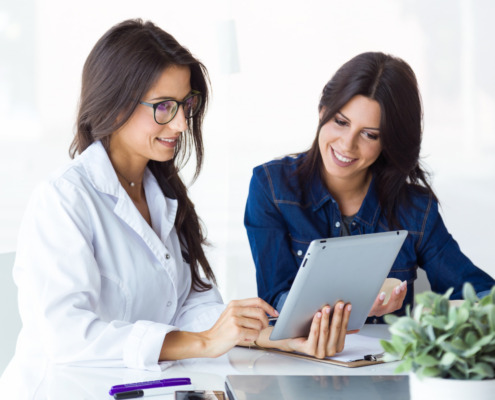 médica avaliando dados no tablet com mulher ao lado junto