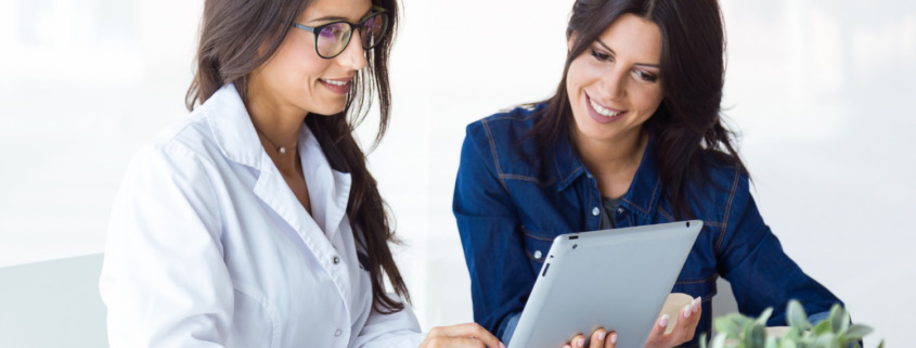 médica avaliando dados no tablet com mulher ao lado junto