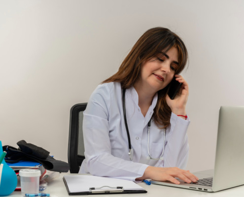 médica em consultório de jaleco branco falando ao telefone