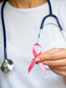 médica com estetoscópio pendurado no pescoço segurando laço rosa