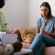 mulher sentada no sofá em atendimento com psicólogo em sua frente