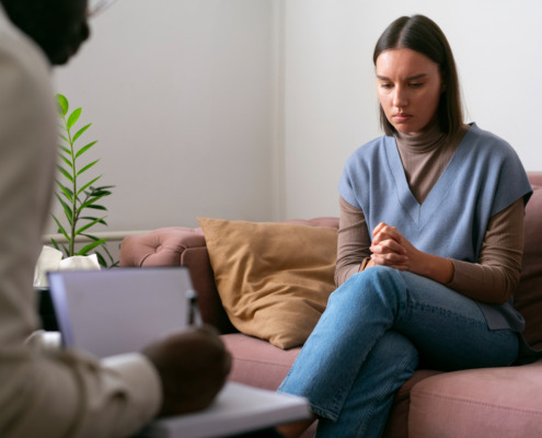 mulher sentada no sofá em atendimento com psicólogo em sua frente