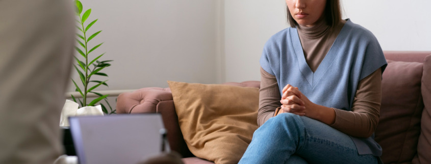 mulher sentada no sofá em atendimento com psicólogo em sua frente