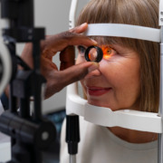 idosa faz exame de vista em aparelho dentro do consultório médico