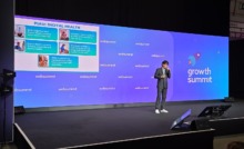 homem palestrando em palco de evento com painel com slide ao fundo