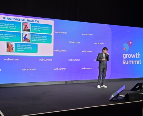 homem palestrando em palco de evento com painel com slide ao fundo
