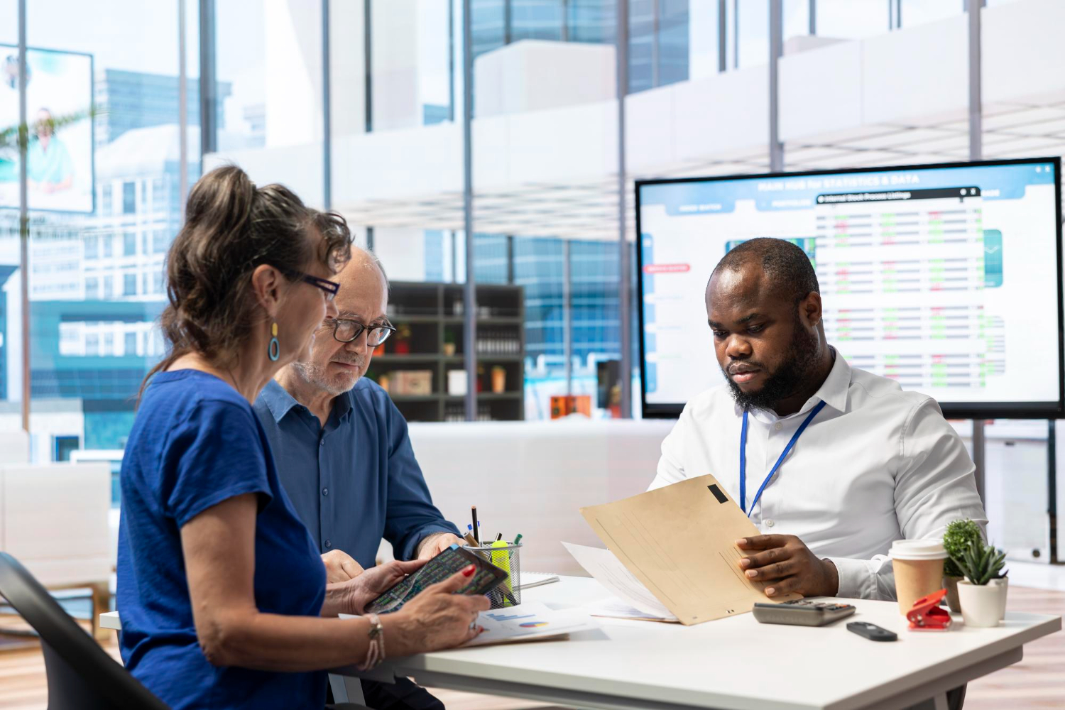 profissionais em sala de reunião com papeis na mesa e tela ao fundo