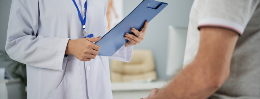 médica em consultório segura prancheta e paciente sentado em maca