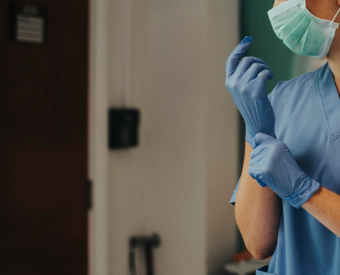 enfermeira de azul com máscara de proteção e luva descartável