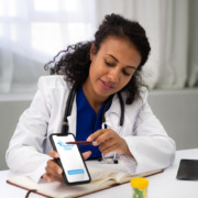 médica em consultório mostrando aplicativo em celular