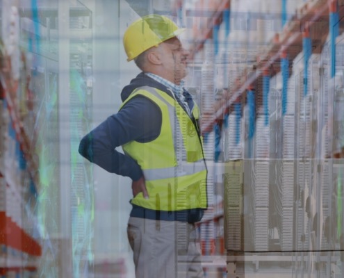 funcionário com colete e capacete amarelo, com as mãos nas costas, indicando dor