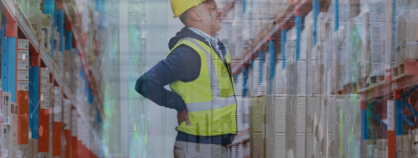 funcionário com colete e capacete amarelo, com as mãos nas costas, indicando dor