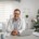 médico em consultório sorrindo e com notebook na mesa
