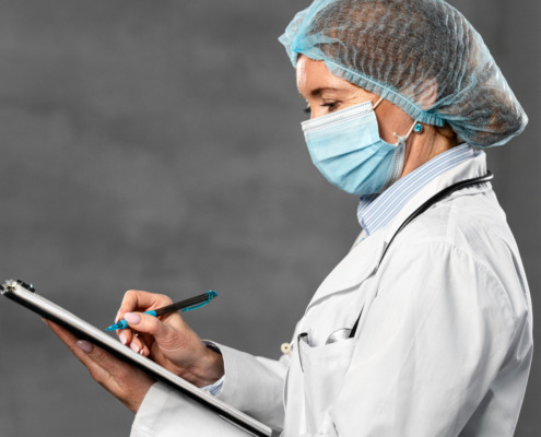 médica com másca preenchendo papel em prancheta