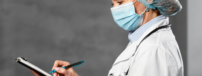 médica com másca preenchendo papel em prancheta