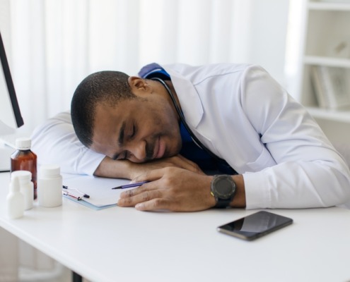 médico em consultório com cabeça na mesa