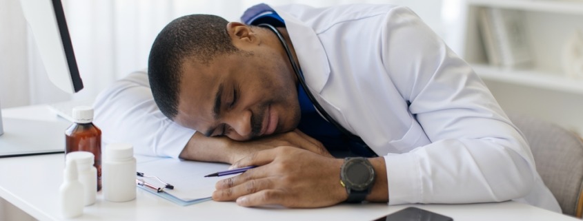 médico em consultório com cabeça na mesa