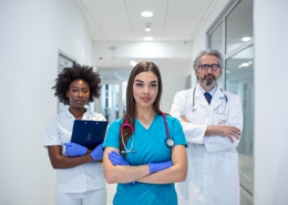 três médicos em pé em corredor de hospital