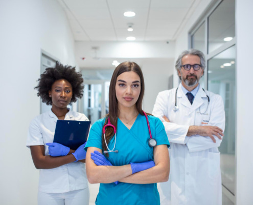 três médicos em pé em corredor de hospital