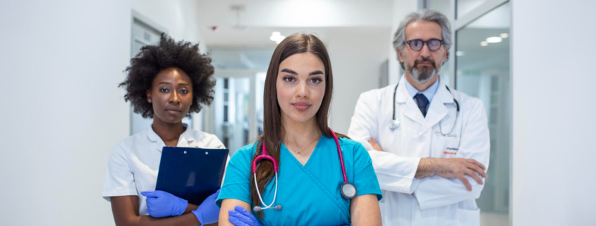 três médicos em pé em corredor de hospital