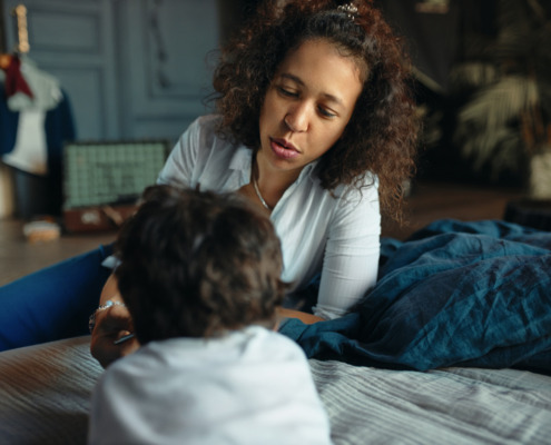 mãe conversando com filho na cama