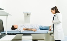 ´paciente deitada em máquina de desitometria óssea com médica ao lado