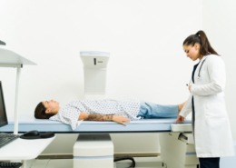 ´paciente deitada em máquina de desitometria óssea com médica ao lado