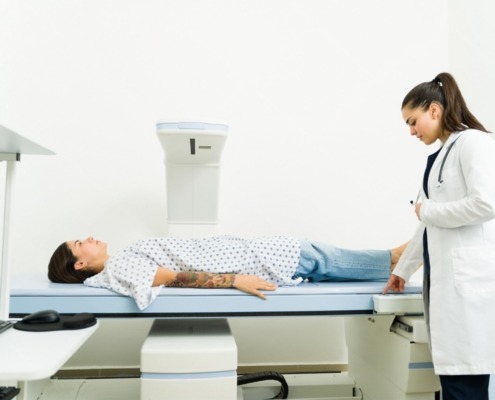 ´paciente deitada em máquina de desitometria óssea com médica ao lado