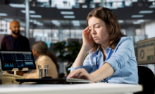 funcionária em mesa de escritório com aspecto de cansaço físico e mental